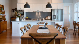 wooden dining table with kitchen in background