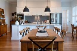 wooden dining table with kitchen in background