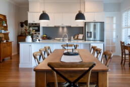 wooden dining table looking through to hamptons style kitchen