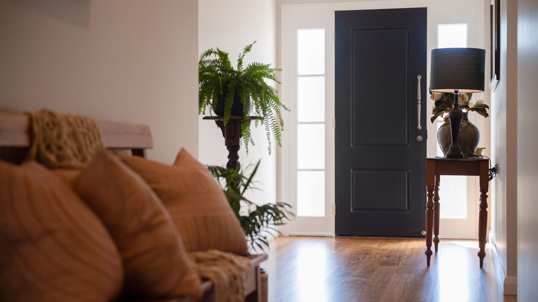 entryway with black door and wooden floor boards