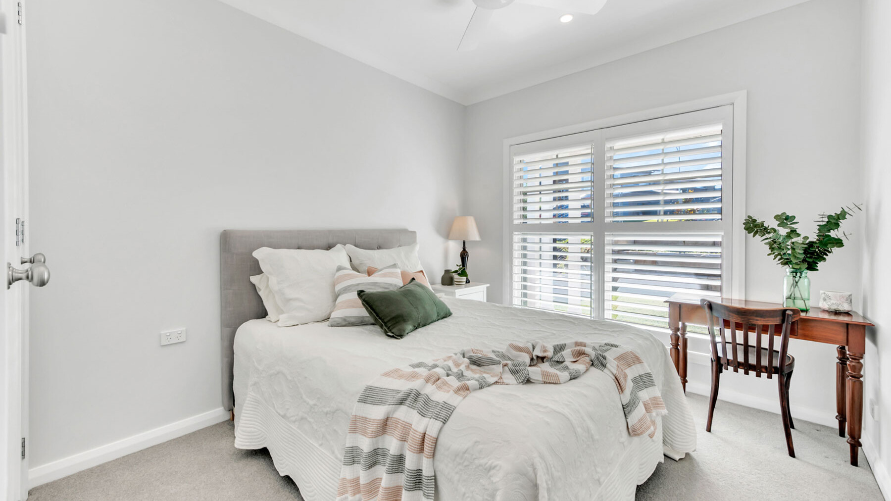 white spacious bedroom with plantation shutters