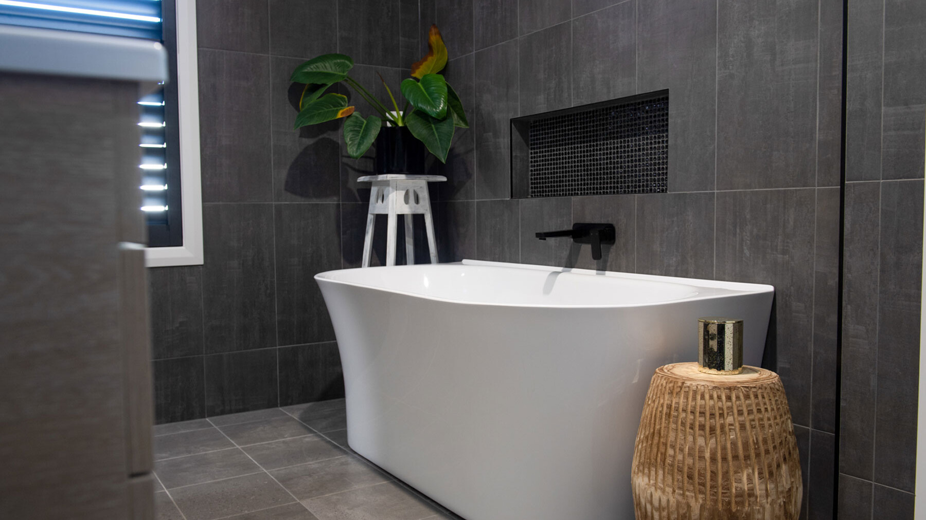 charcoal grey tiled bathroom with large freestanding bath