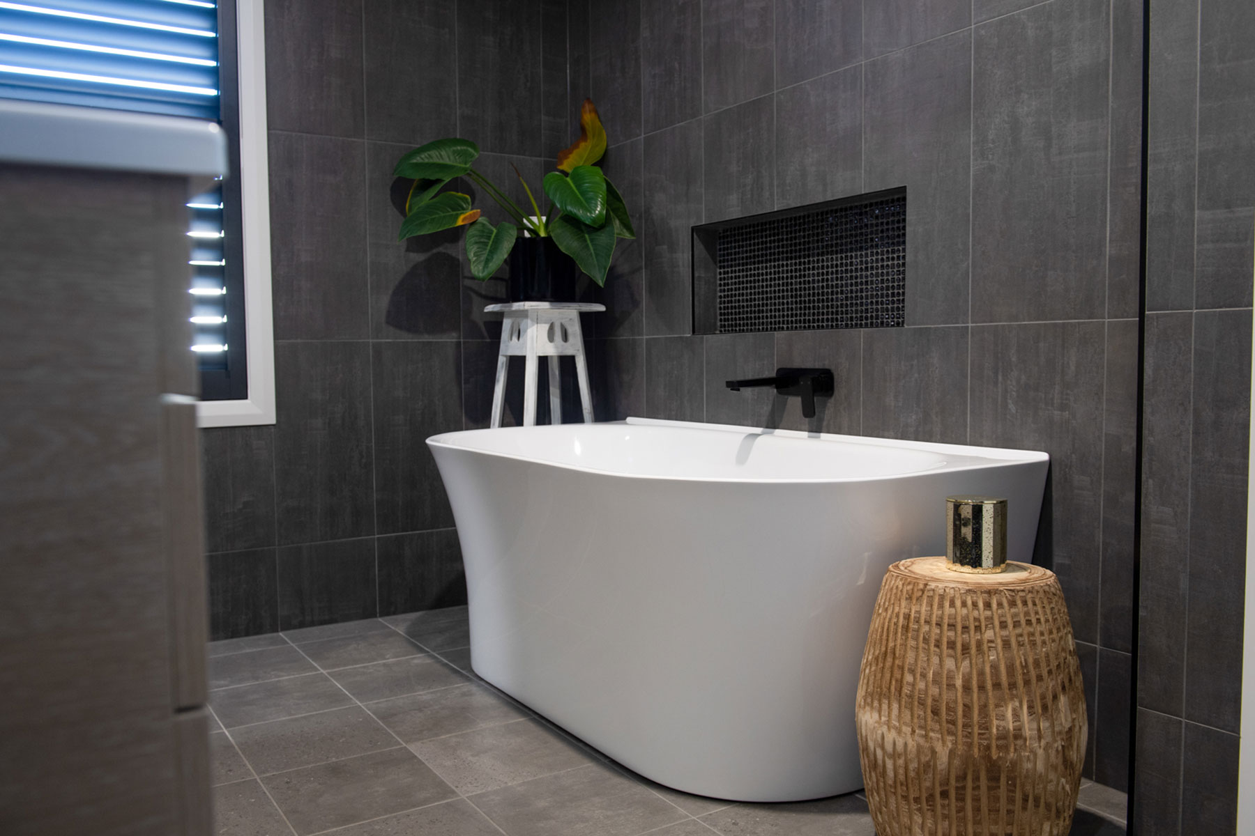 charcoal grey tiled bathroom with large freestanding bath