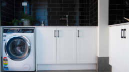 spacious laundry with black tile splashback