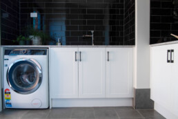 spacious laundry with black tile splashback