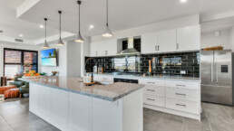 white gallery style kitchen with black tiled splashback